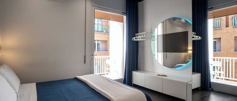 Una habitación de hotel moderna con cama, televisión, espejo y vistas al balcón.