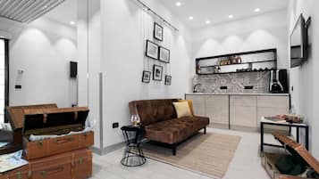 Una sala de estar moderna con un sofá, una mesa de centro y una chimenea. Hay maletas y una guitarra en la habitación.