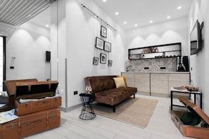 Una sala de estar moderna con un sofá, una mesa de centro y una chimenea. Hay maletas y una guitarra en la habitación.