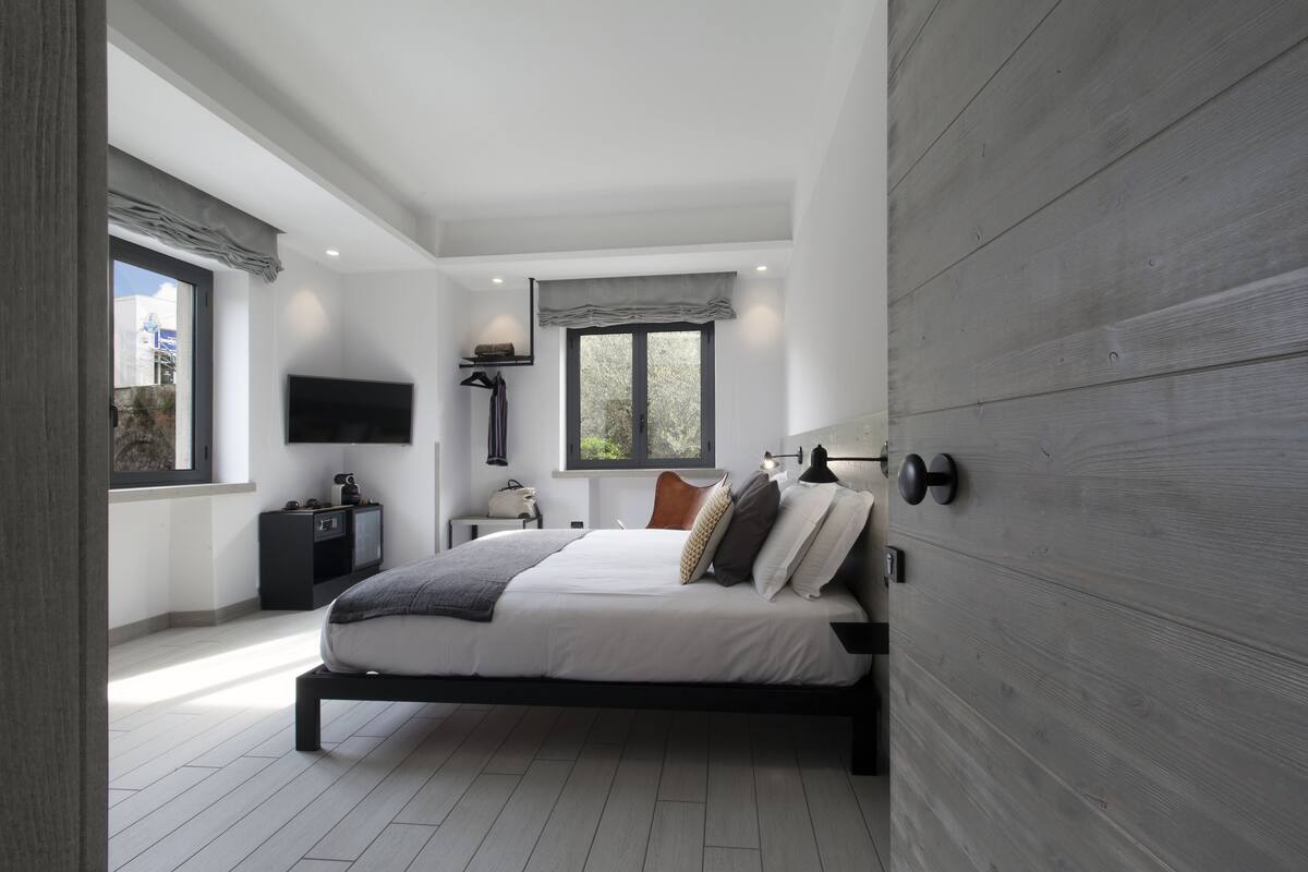 Une chambre moderne avec un lit, une télévision, une fenêtre et un mur en bois.