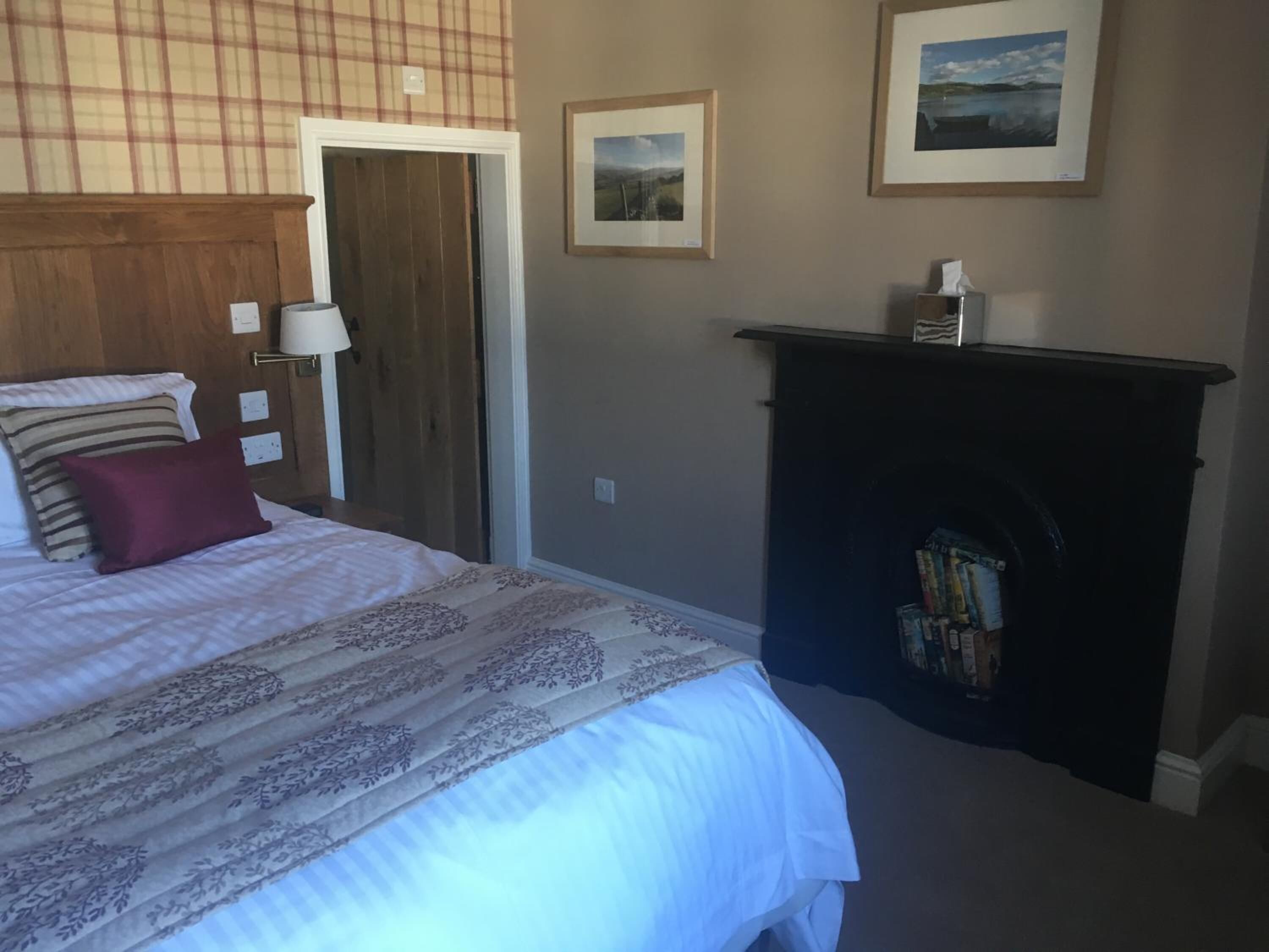 Un dormitorio con cama, chimenea y dos cuadros en la pared.