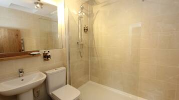 A modern bathroom with a glass-enclosed shower, a white sink, and a toilet.