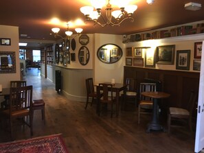 A cozy interior with wooden floors, a chandelier, and a bar area with chairs and tables. - Plas Yn Dre (Bala)