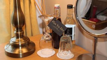 Una mesa de madera con una lámpara de latón, una botella de perfume, un frasco de vidrio y un espejo redondo.