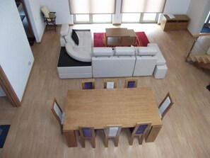 Un salon moderne avec un ensemble de canapés, une table à manger en bois et un escalier.