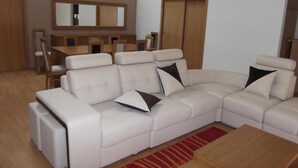 A modern living room with a sectional sofa, a wooden coffee table, and a dining area with a wooden table and chairs. - Quinta dos Caibrais (Oliveira de Frades)