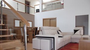 A spacious living area with a modern sofa set, a wooden staircase, and a red carpet. - Quinta dos Caibrais (Oliveira de Frades)