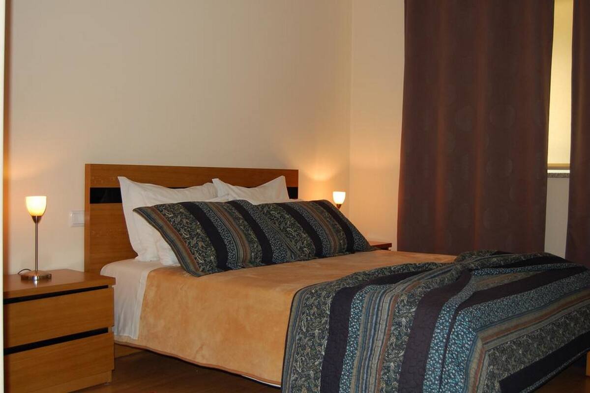 Ein Einzelbett mit Holz Kopfteil, zwei Nachttischen und einer gemusterten Tagesdecke.