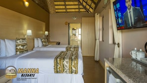 A hotel room with two beds, a TV, a desk, and a bathroom visible through an open door.