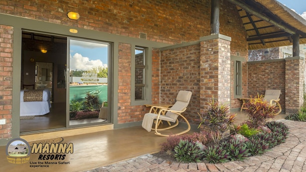 A brick building with a glass door entrance, a lounge area with a rocking chair, and a sign for Manna Resorts.
