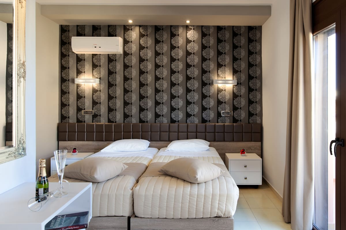A hotel room with a large bed, two bedside tables, a mirror, and a patterned wallpaper.