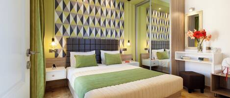 A modern bedroom with a large bed, green bedding, a geometric-patterned headboard, bedside tables with lamps, a mirror, and a small desk with a vase of flowers.