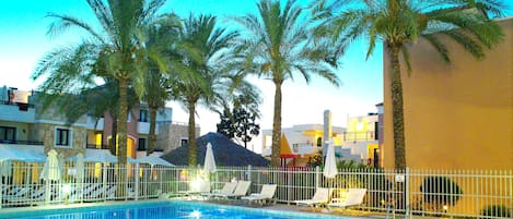Una piscina al aire libre, sombrillas, sillones reclinables de piscina