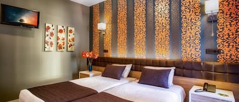 A double bed with a brown headboard, a bedside table with a lamp, and a wall-mounted phone.