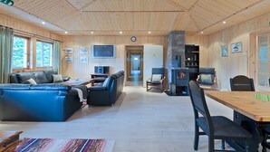 A spacious living area with a wooden ceiling, a blue sofa, a wooden dining table, and a fireplace.