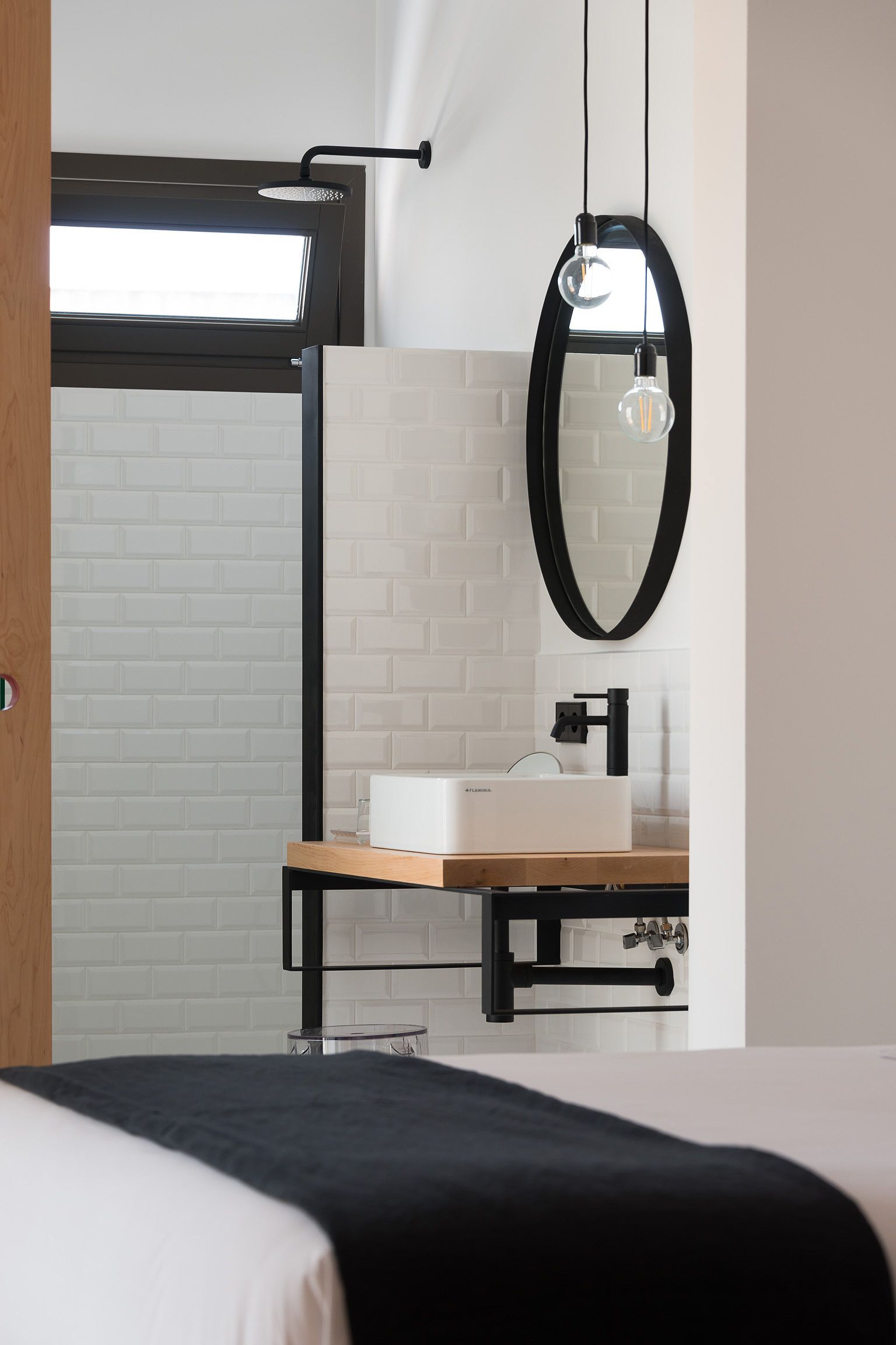 Een moderne badkamer met dakraam, een witte wastafel en een spiegel met zwart frame.
