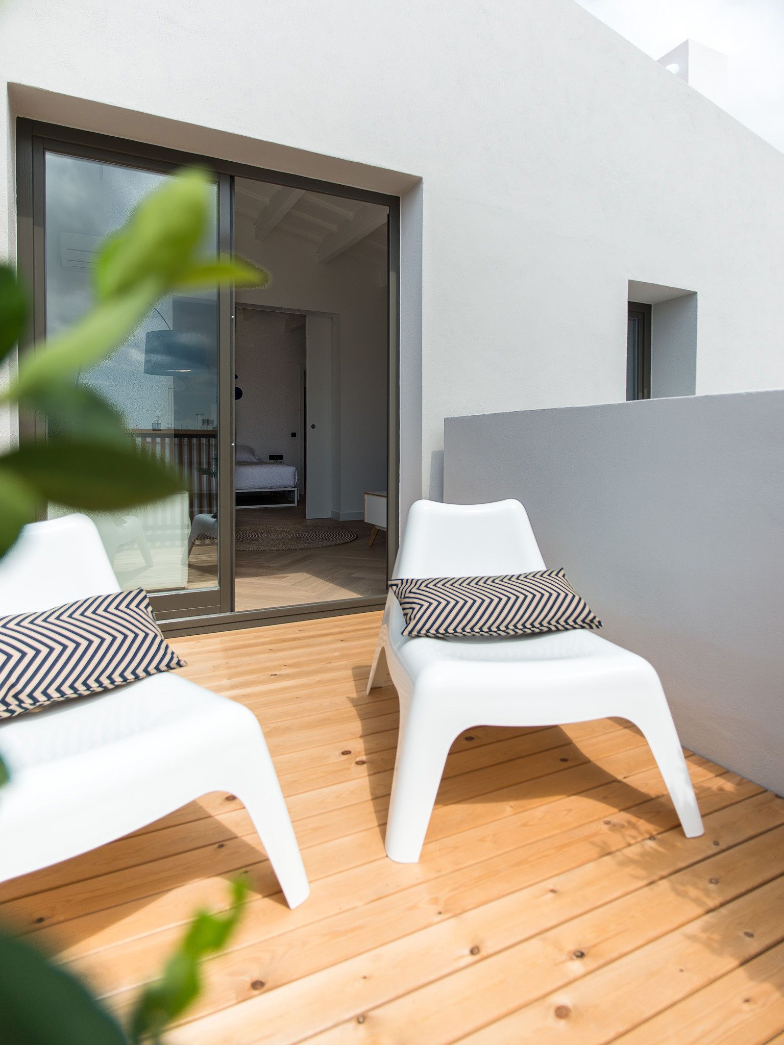 Un área de estar al aire libre con estilo, con dos sillas blancas y una terraza de madera.