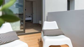 Un área de estar al aire libre con estilo, con dos sillas blancas y una terraza de madera.