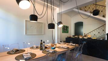 A modern dining area with a long table, clear chairs, and pendant lighting.