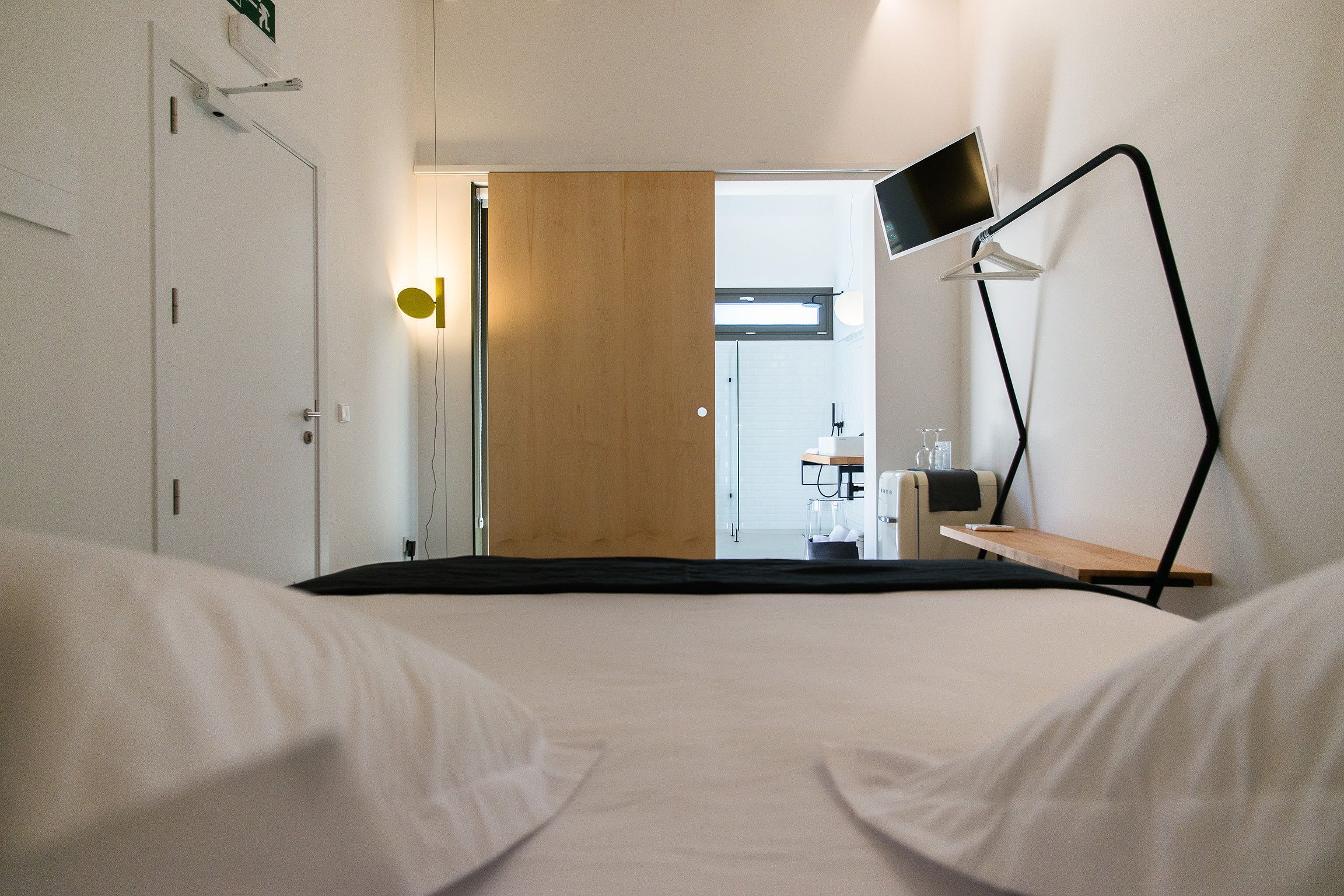Una camera d'albergo con un letto, una scrivania, una sedia, una televisione e un bagno visibile attraverso una porta aperta.