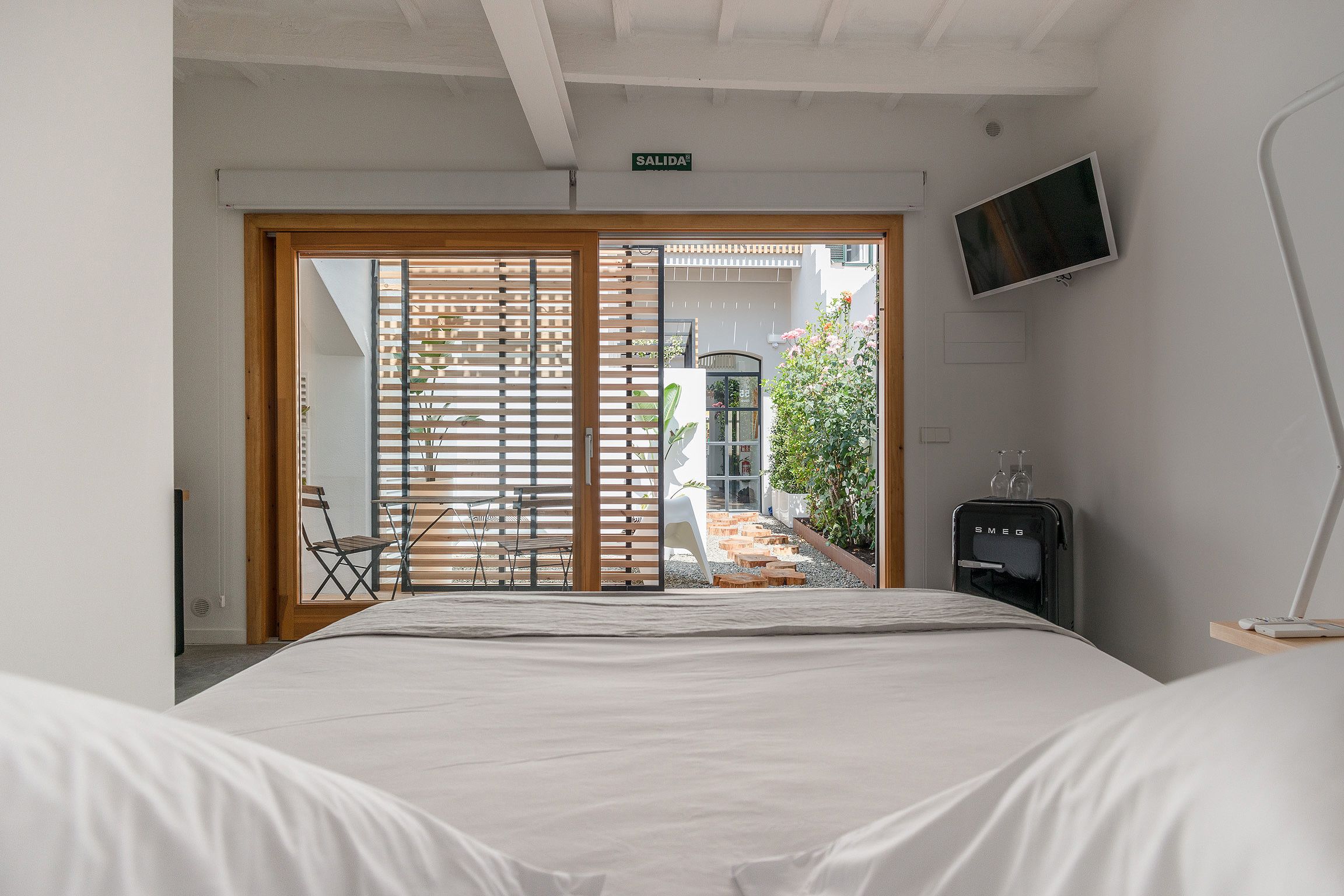 A bedroom with a bed, a TV mounted on the wall, and a water dispenser.