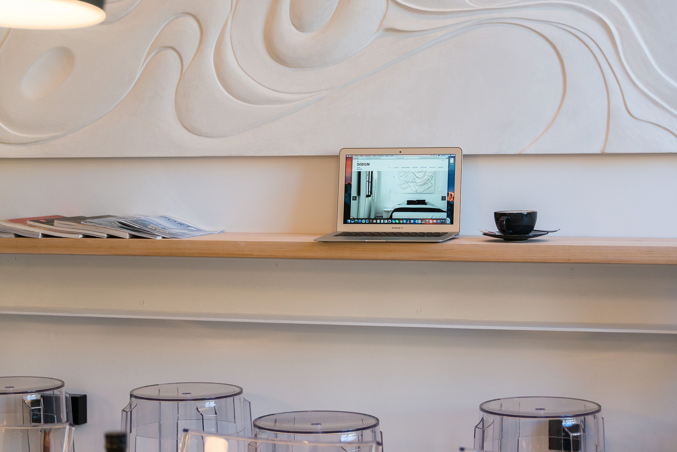 A laptop on a shelf with a cup beside it, and several clear containers below.