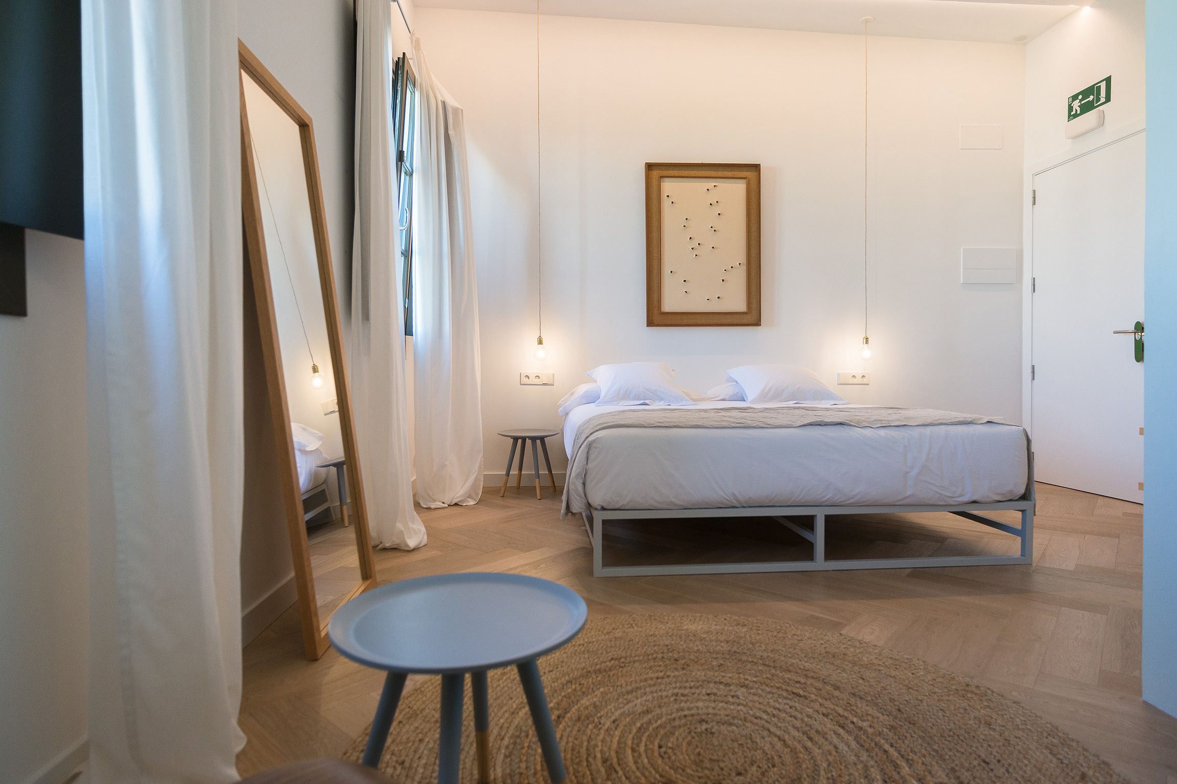 Un dormitorio con cama, mesita de noche y lámpara colgante.