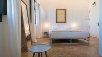 Un dormitorio con cama, mesita de noche y lámpara colgante.