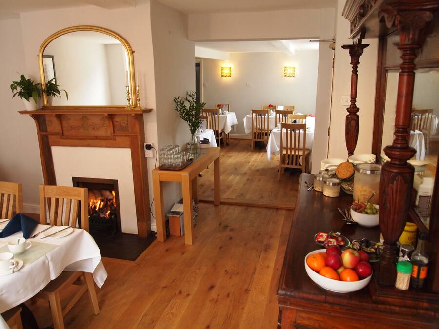 A dining area with wooden furniture, a fireplace, and a mirror.