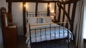 A traditional room with a four-poster bed, wooden beams, and a nightstand with a lamp. - Chantry Hotel (Bury St Edmunds)