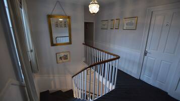 A staircase with a white railing, a chandelier, and framed pictures on the walls.