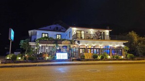 Un edificio de dos pisos con un restaurante en la planta baja y un balcón en el nivel superior.