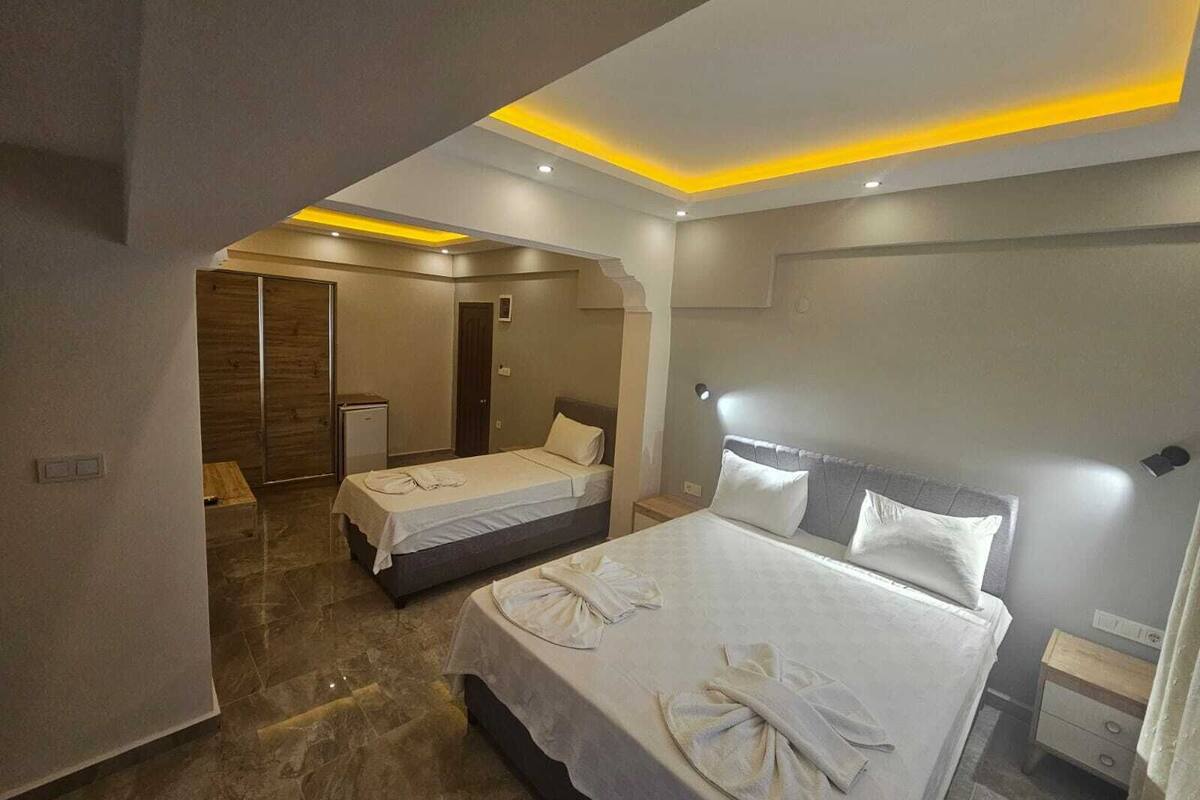 Une chambre d’hôtel moderne dotée d’un grand lit, d’un lit plus petit et d’un dressing.