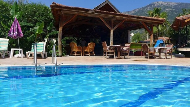 Una piscina con sillas de descanso y una zona de estar techada.