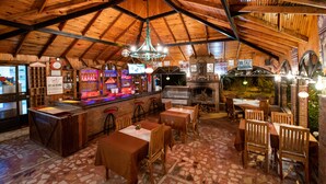 Un comedor interior con mesas y sillas de madera, una barra y una chimenea.
