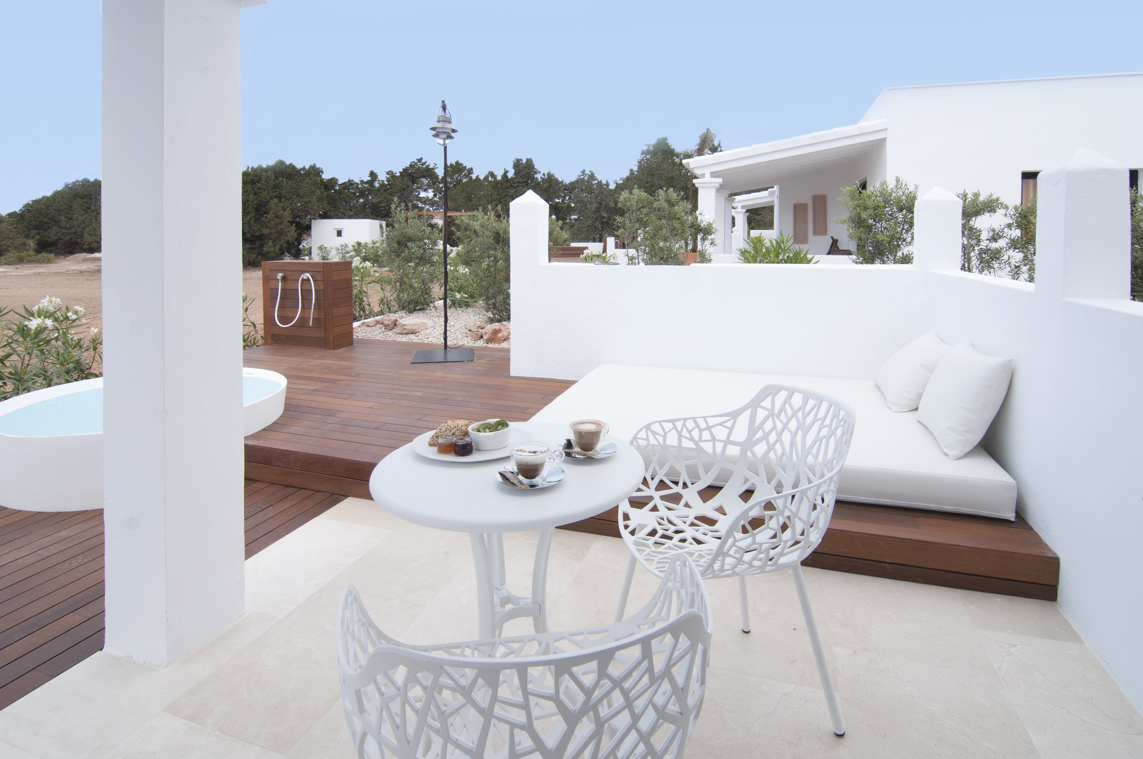 A white outdoor seating area with a table, chairs, and a small pool.