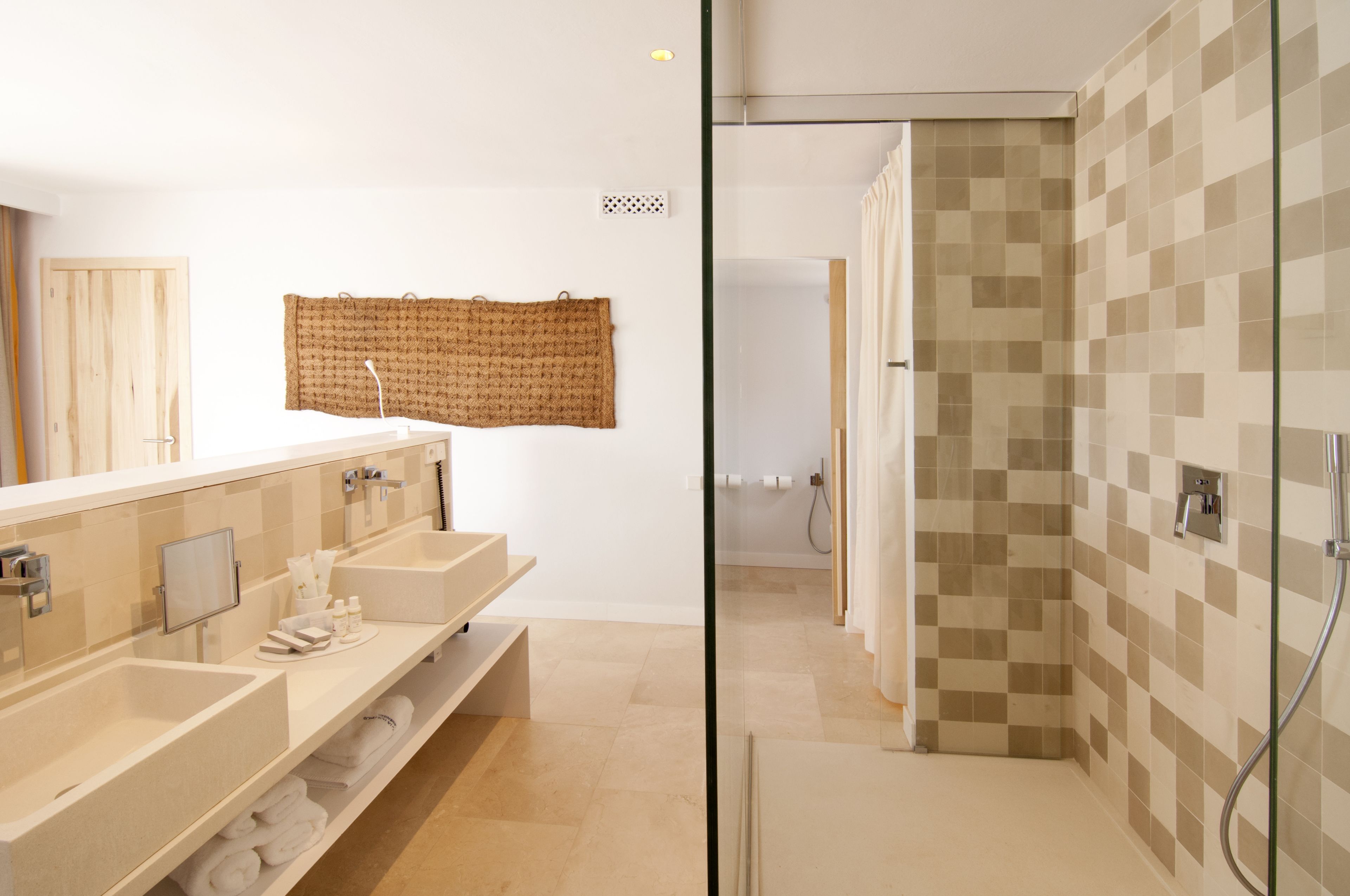 Un baño moderno con dos lavamanos, un espejo grande y una zona de ducha.