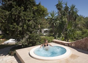 Lämminvesiallas, jonka ympärillä on vehreää kasvillisuutta ja kivimuuri.