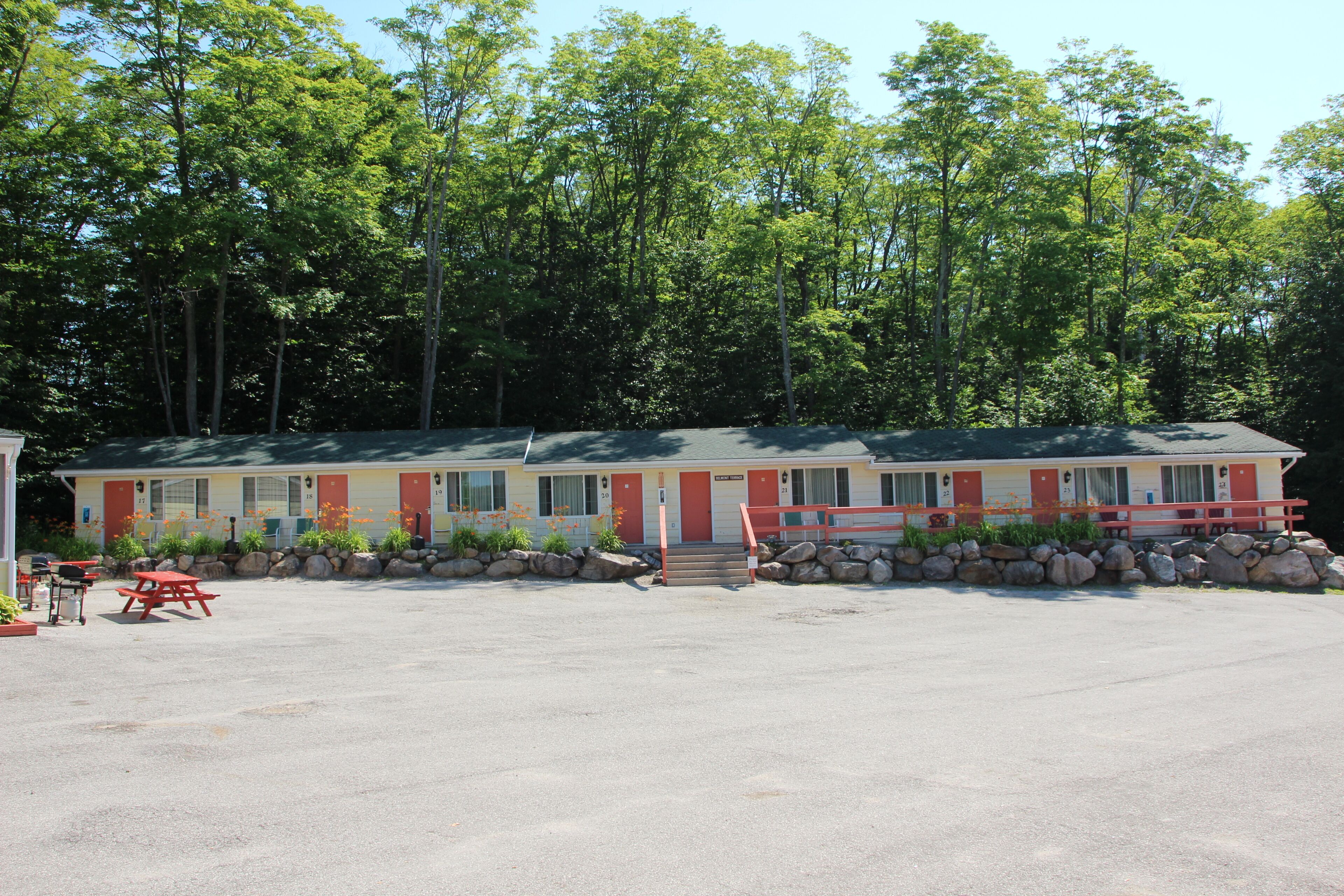 A motel with a row of rooms, a covered parking area, and a picnic table.