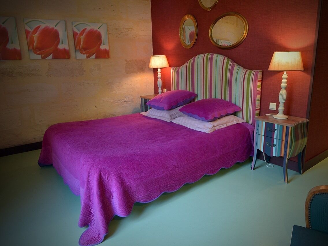 A bedroom with a bed, two bedside tables, and a wall with three framed pictures.