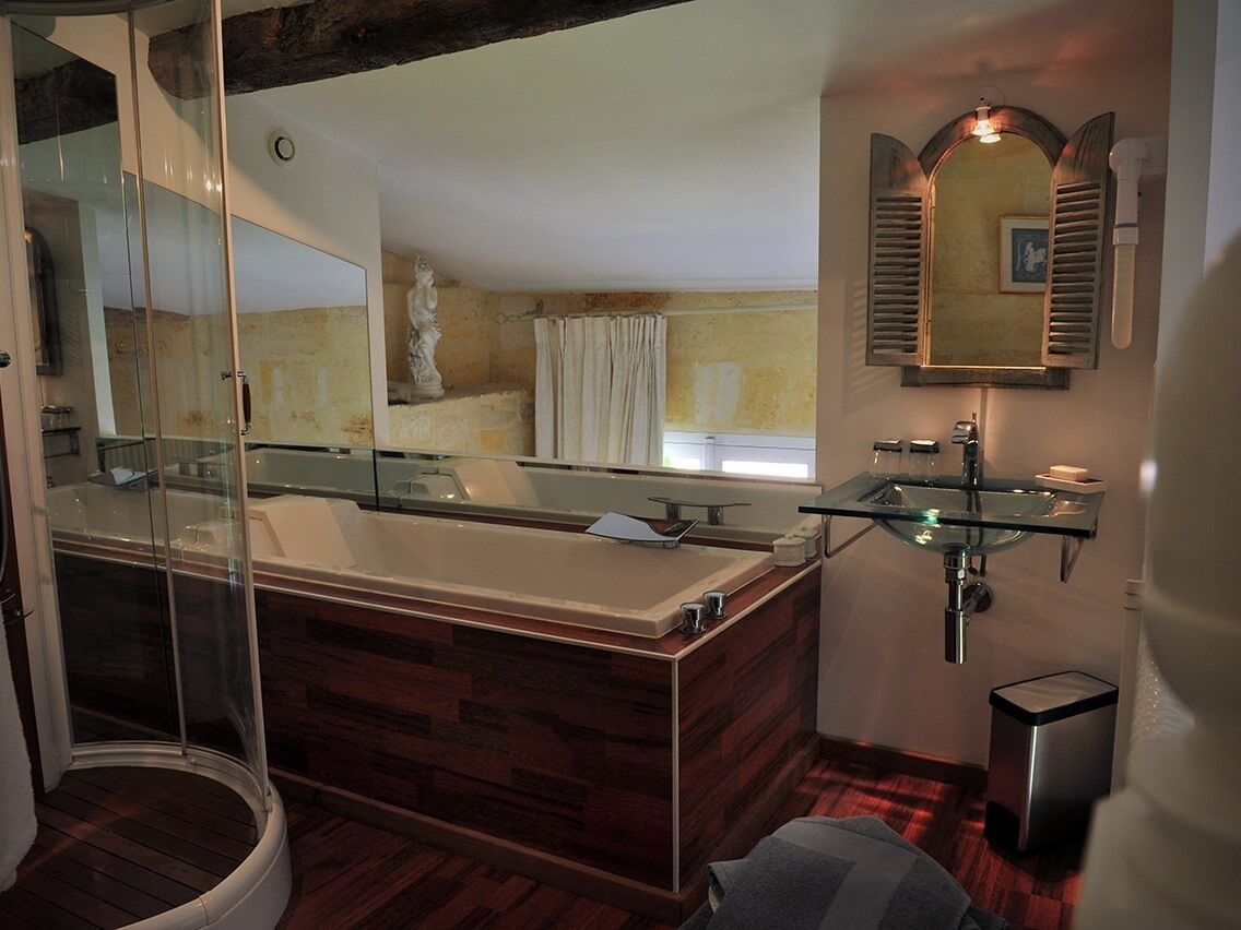 A modern bathroom with a glass-enclosed shower, a wooden bathtub, and a glass sink.