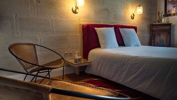 A bedroom with a bed, two wall-mounted lights, a chair, and a nightstand with a tissue box.