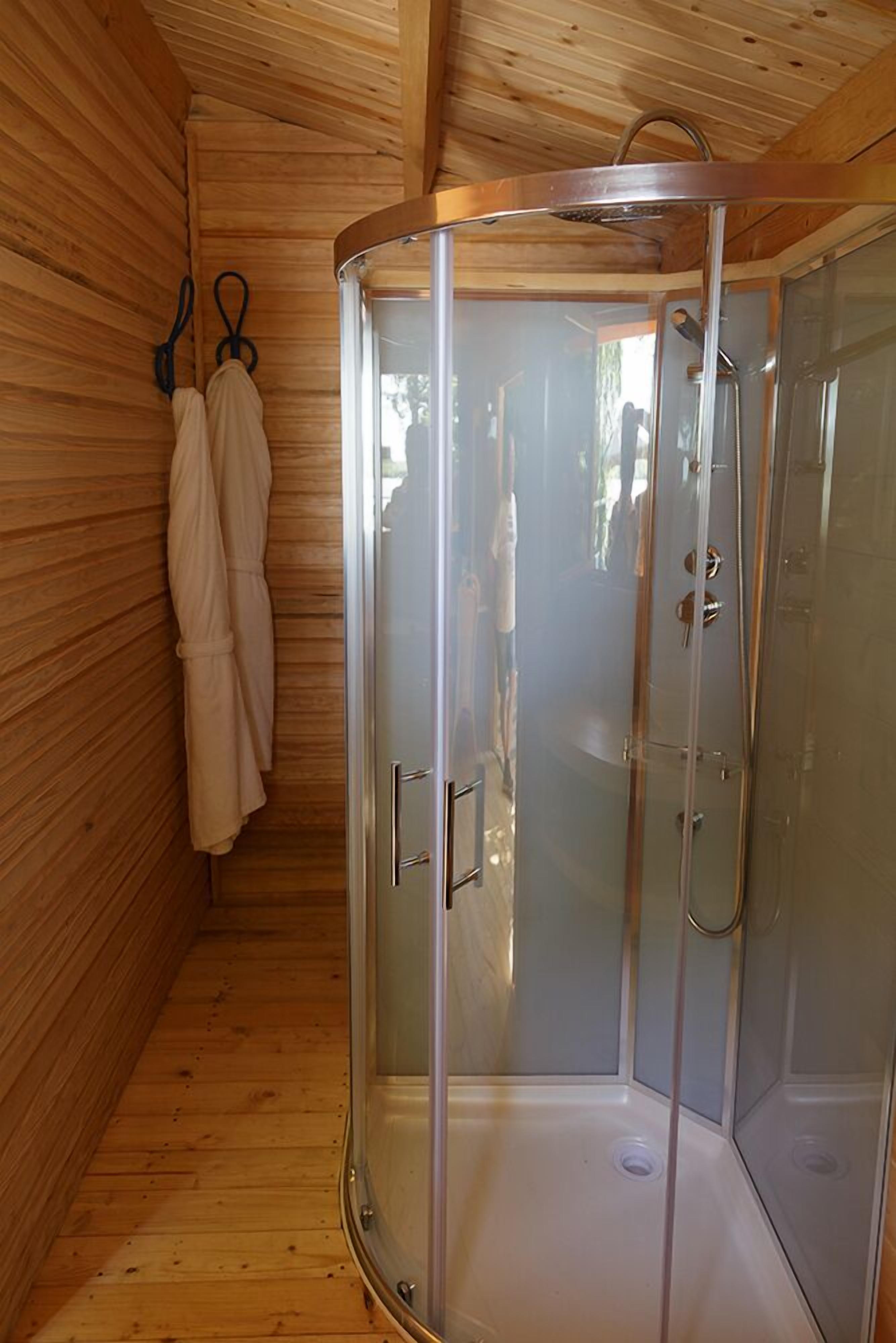 A glass-enclosed shower with a wooden interior, a towel rack, and a visible showerhead.