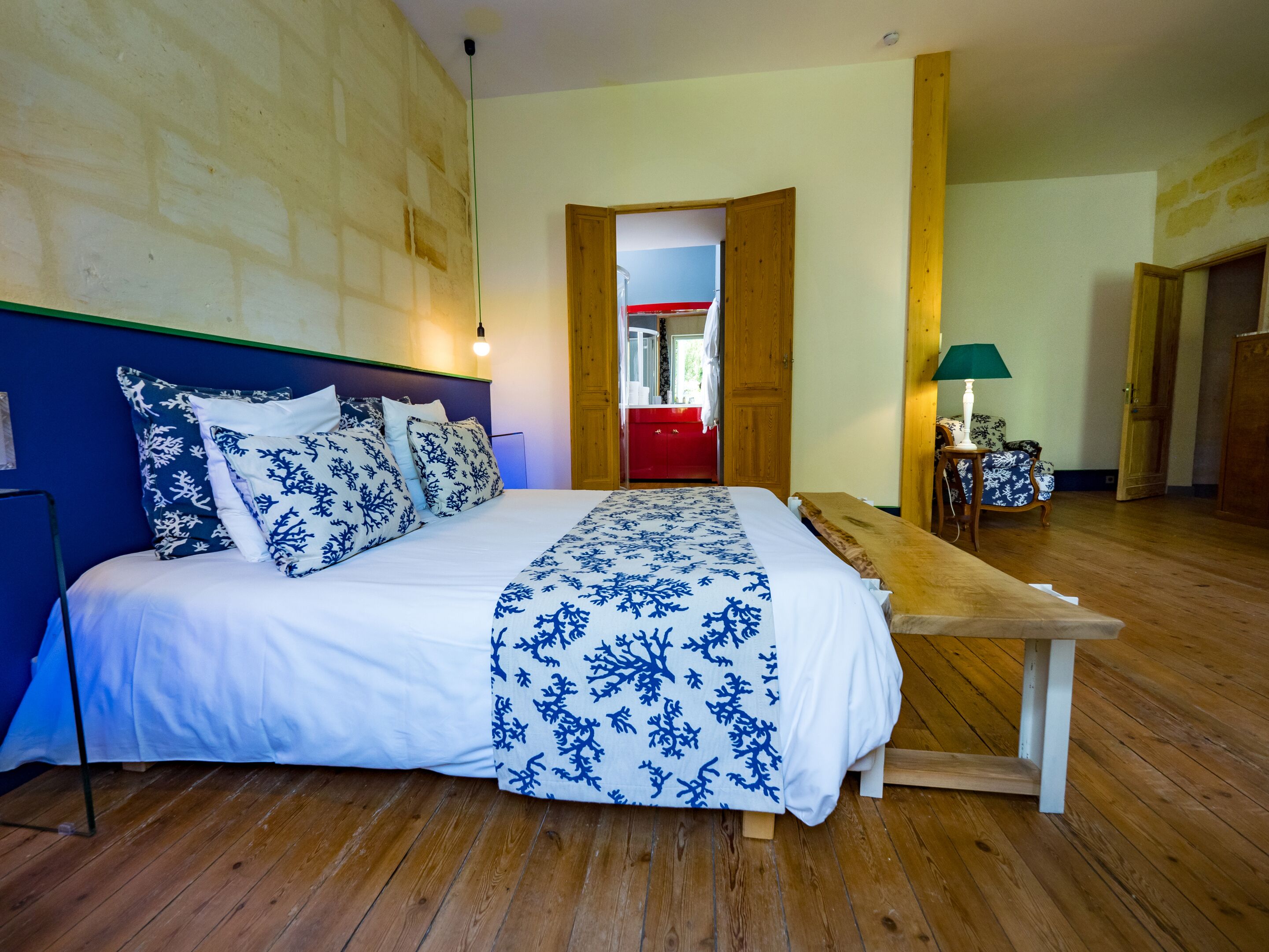 Camera da letto con un letto, pavimento in legno e una panca.