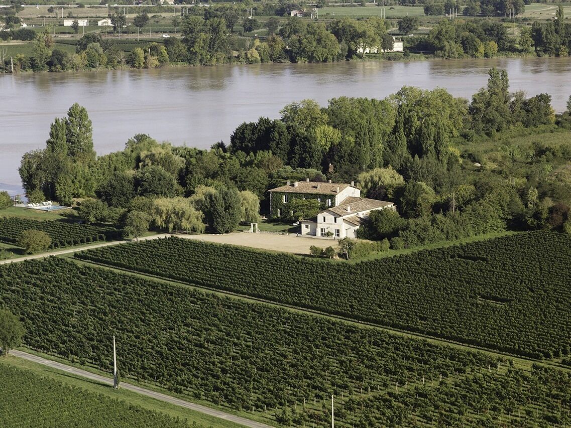 Ein weitläufiges Anwesen mit einem Haus, umgeben von üppiger Vegetation und einem Fluss.