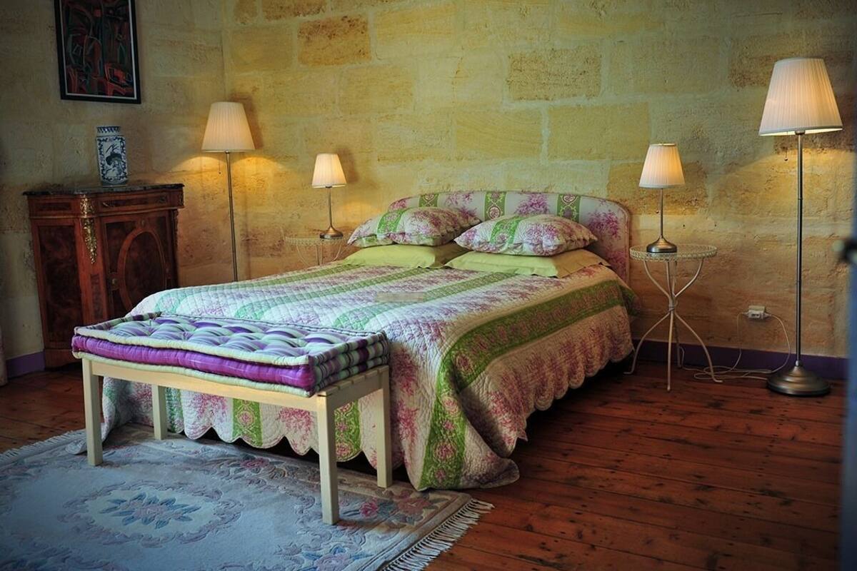 A bedroom with a wooden bed, two bedside lamps, a nightstand, and a rug.