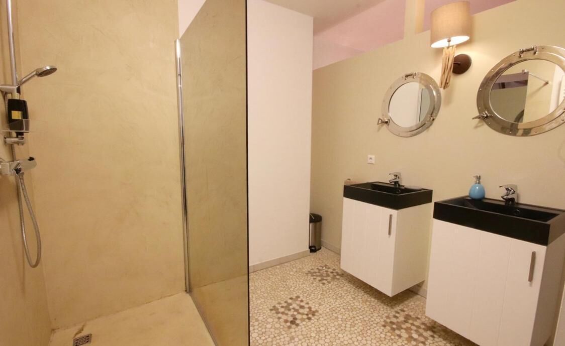 Une salle de bain avec une douche, deux lavabos et deux miroirs.