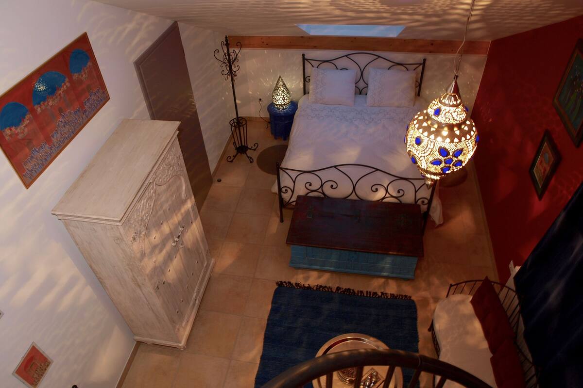 Une chambre à coucher avec un lit, une table de chevet et un luminaire suspendu.