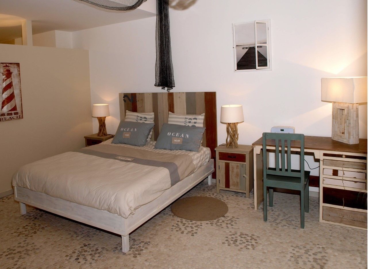 A bedroom with a bed, two bedside tables, a desk, and a chair.