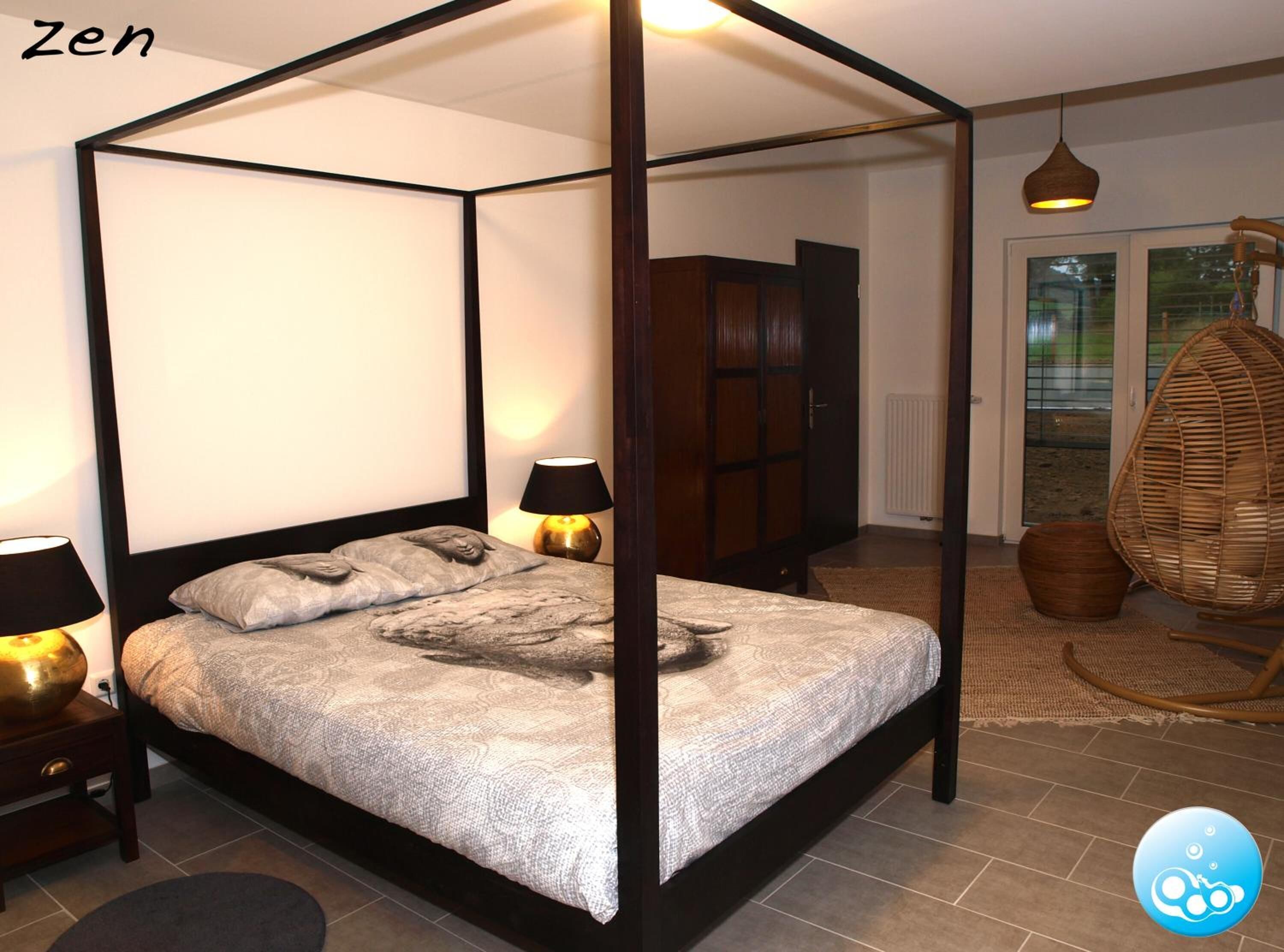 A four-poster bed with a canopy, two bedside lamps, a wicker chair, and a view of the outdoors through a glass door.